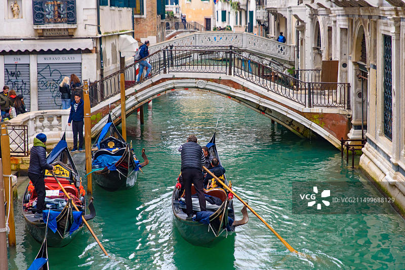 威尼斯运河上的传统贡多拉船及游客图片素材