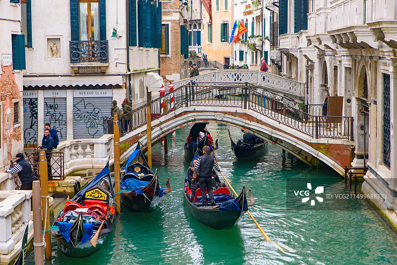 威尼斯运河上的传统贡多拉船及游客图片素材