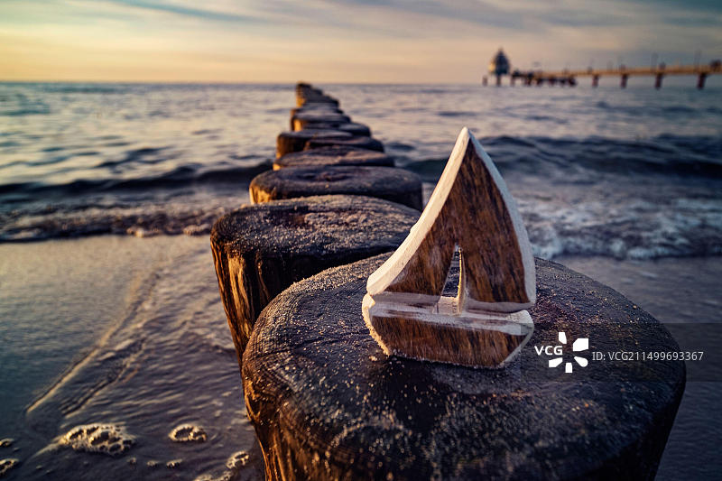 象征旅行和探索的海岸防波堤上的木制帆船模型图片素材
