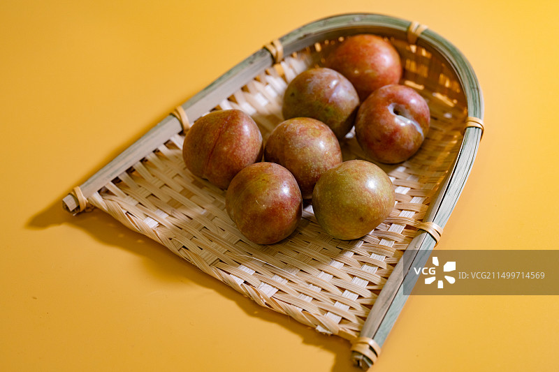 黄色背景的嵊州桃形李子特写镜头图片素材