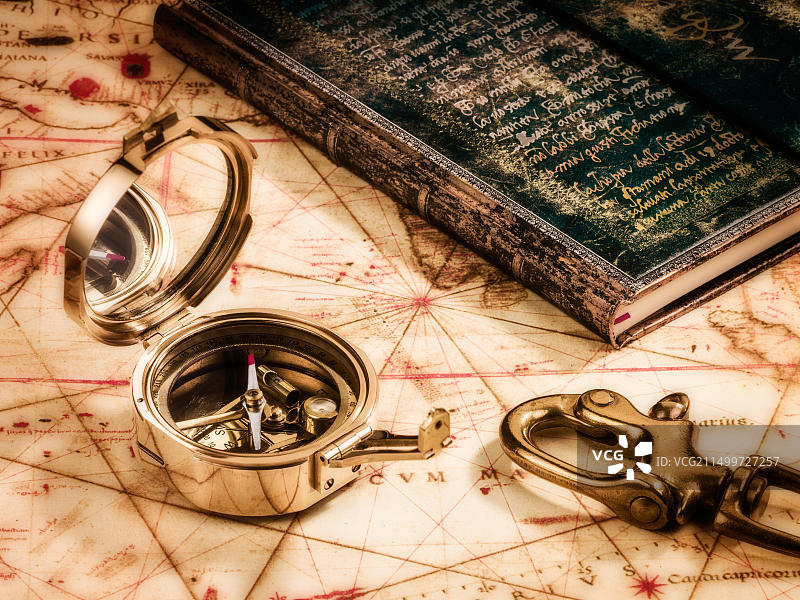 静物：旅行主题，古董黄铜指南针与古旧地图、书籍和船钩图片素材