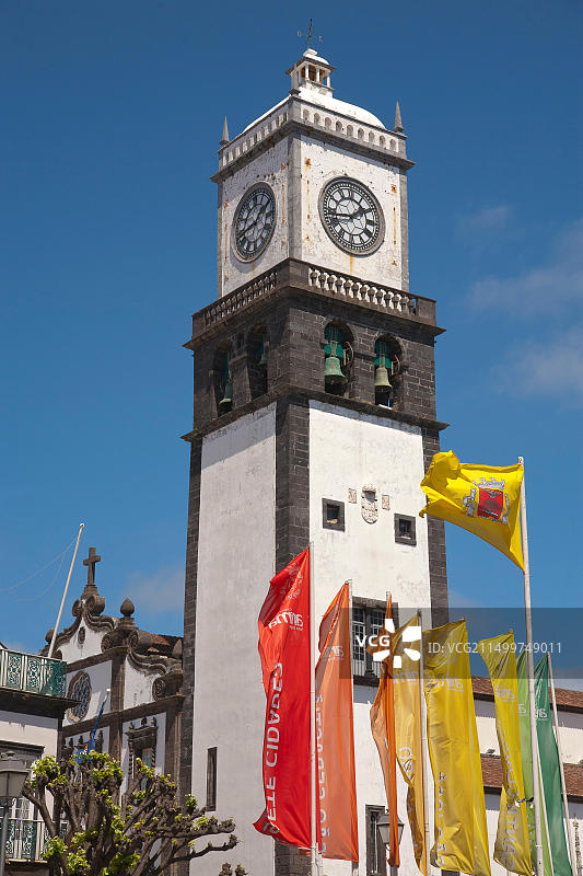蓬塔德尔加达市中心圣塞巴斯蒂昂教堂塔楼景观及市镇村庄名称旗帜，亚速尔群岛，葡萄牙图片素材