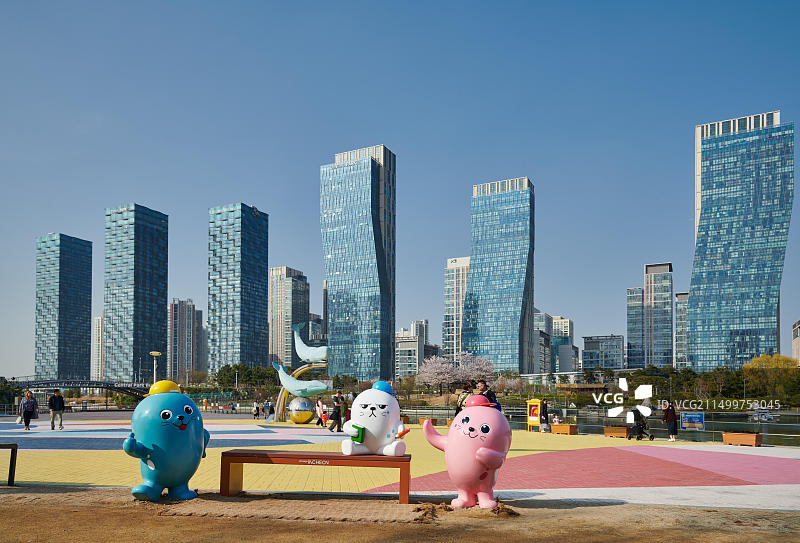 韩国仁川松岛国际商务区中央公园的超大彩色玩具人偶和摩天大楼图片素材