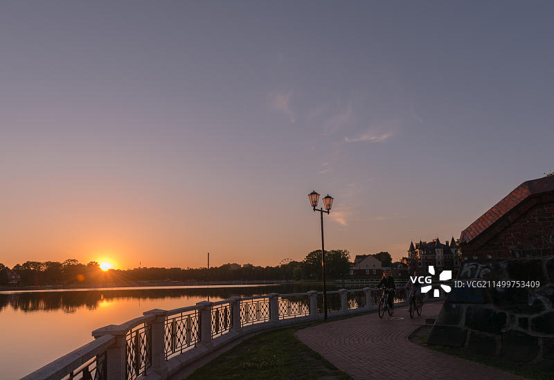 俄罗斯加里宁格勒上湖沿岸的林荫大道，傍晚时分，骑自行车的女孩图片素材