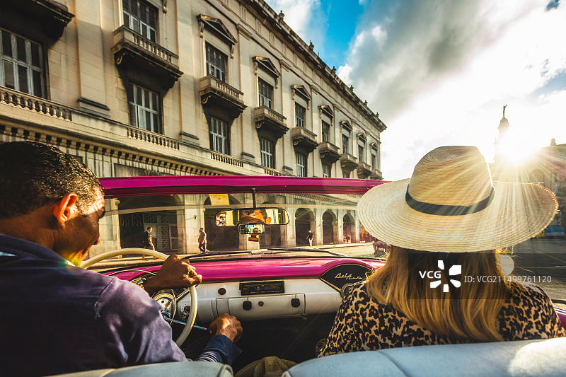 游客在古巴哈瓦那享受日落时分的老爷车之旅图片素材