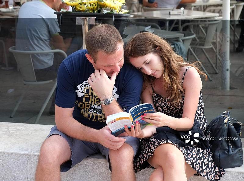 情侣在商业广场阅读葡萄牙里斯本旅游书图片素材