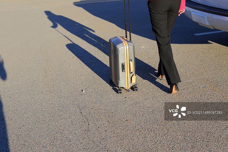 商务女性在机场外拖着行李箱的腿部特写，穿着高跟鞋图片素材