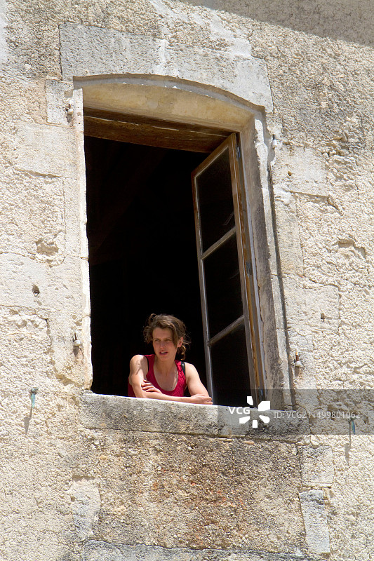 年轻女子在法国昂古莱姆附近的一座农舍窗口向外看图片素材