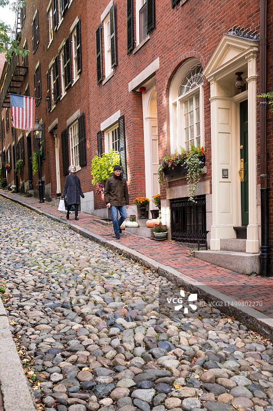 夜晚，在美国马萨诸塞州波士顿历史悠久的 Beacon Hill 鹅卵石街道上行走的人们图片素材