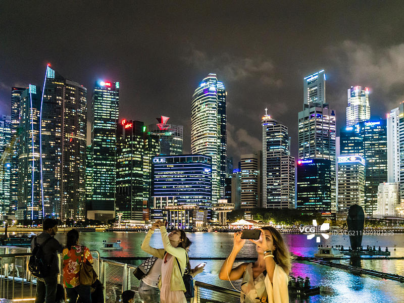 新加坡滨海湾的游客在城市天际线前拍照和自拍。图片素材