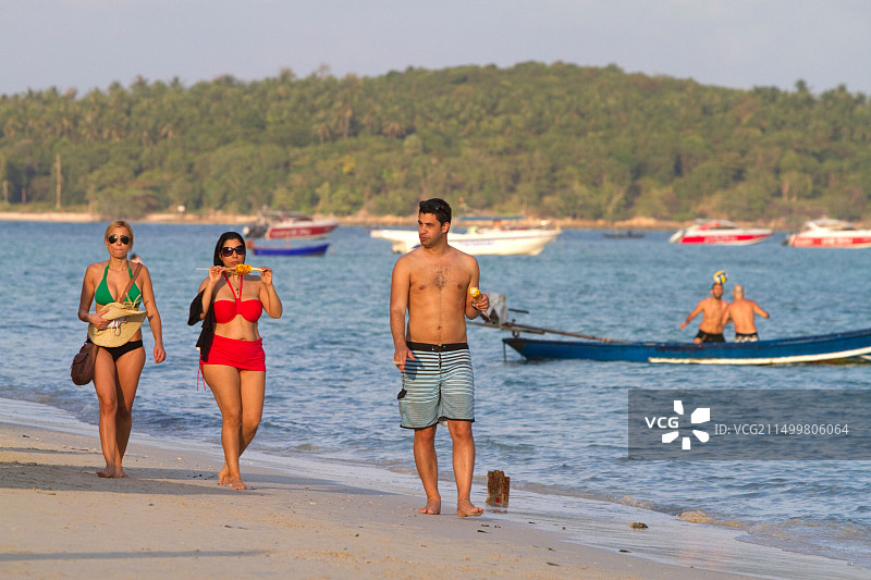 女人在泰国苏梅岛查汶海滩吃烤玉米图片素材