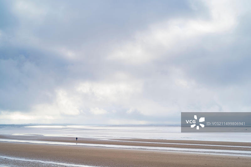 孤独的身影漫步在英国萨默塞特郡伯纳姆滨海沙滩上图片素材