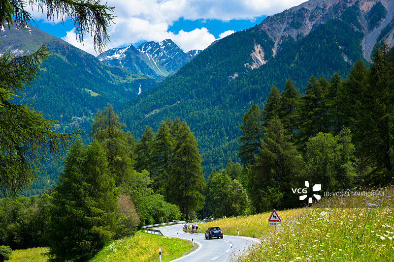 瑞士国家公园内，汽车超越骑行者图片素材