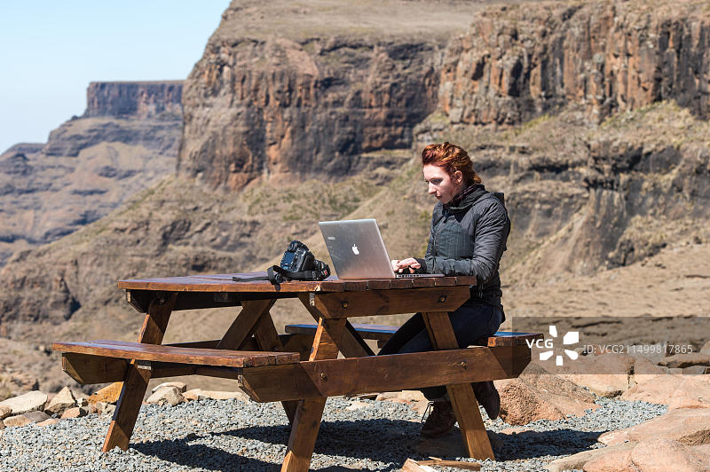 年轻女人在非洲莱索托山区的一张野餐桌旁用笔记本电脑工作图片素材