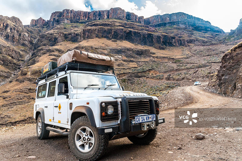 路虎卫士停在南非和莱索托之间的萨尼山口山区的土路边缘图片素材