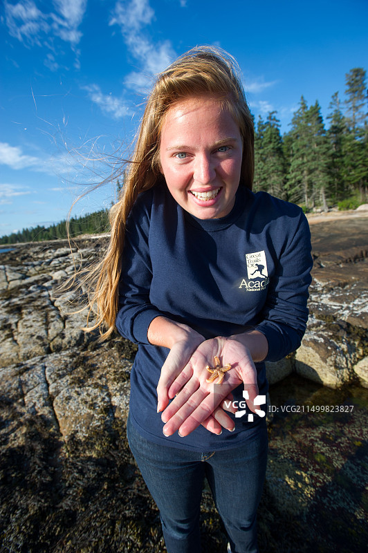 女子在阿卡迪亚国家公园海岸度假，手拿海星图片素材