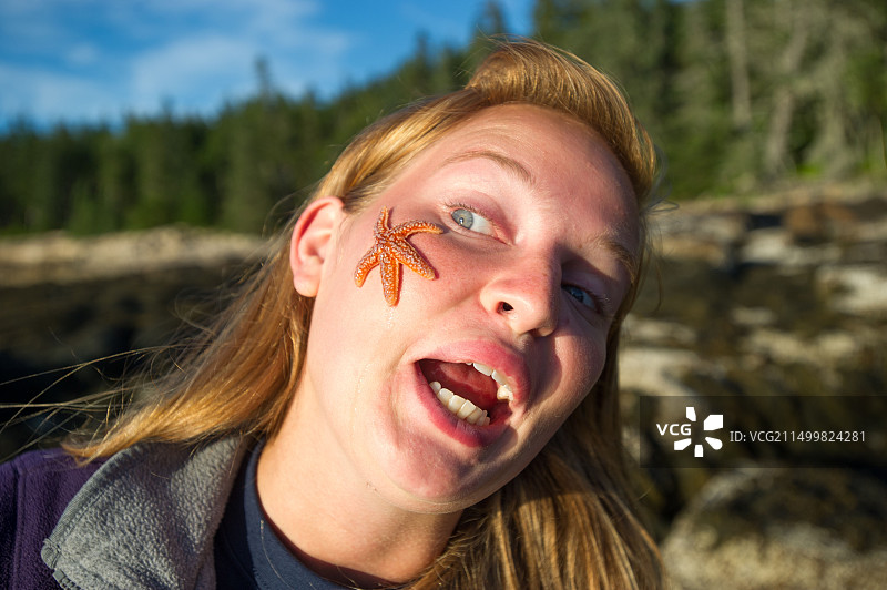 在阿卡迪亚国家公园海岸脸上放着海星的女人图片素材