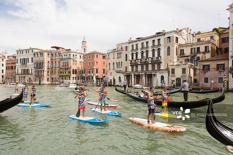 在意大利威尼斯大运河上用桨板站立划水的活跃游客群体图片素材
