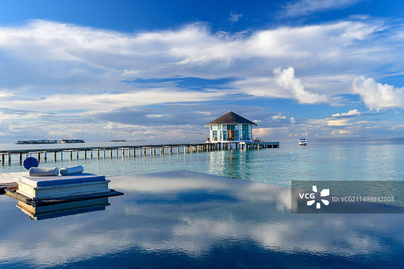 清晨，马尔代夫美拉多岛莱佛士五星级度假酒店的无边泳池和木栈道图片素材