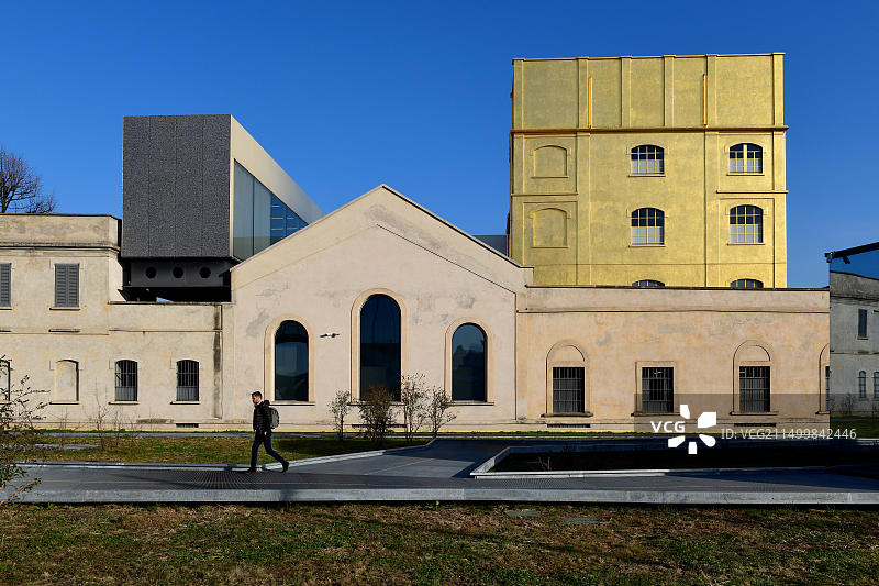 一人走过米兰辛比奥斯新区阿德里亚诺·奥利维蒂广场，远处是普拉达基金会建筑群和鬼屋图片素材