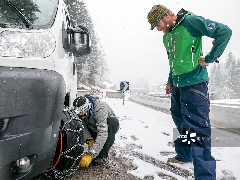在意大利北部多洛米蒂山脉，美国滑雪者在租赁面包车上安装链条图片素材