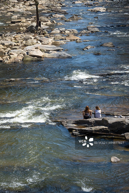 两名年轻女子欣赏佐普溪的风景，佐普溪是查塔胡奇河的支流，沿着佐普溪磨坊遗址，靠近佐治亚州亚特兰大图片素材