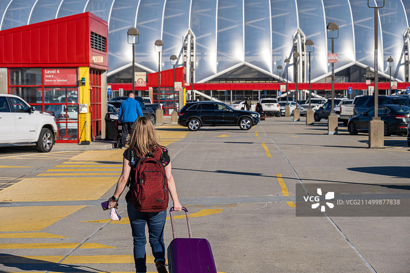 在亚特兰大哈茨菲尔德-杰克逊国际机场停车场，拖着行李箱、背着背包的女游客图片素材
