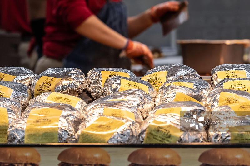 在乔治亚州华纳罗宾斯的Buc-ee's, Buc-ee的员工在装满猪肉烧烤三明治的加热托盘后面切肉。(美国)图片素材