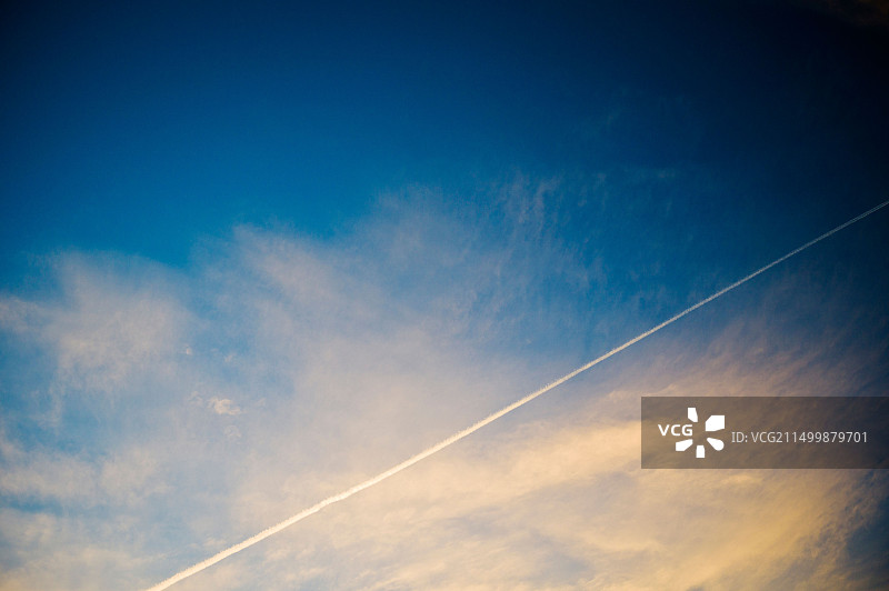晴朗的黄昏日落蓝天上的商用飞机凝结尾迹图片素材