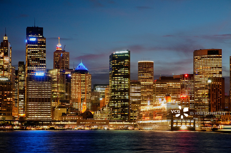 冠达伊丽莎白女王号邮轮停靠在海外客运码头，日落时分的悉尼中央商务区天际线图片素材