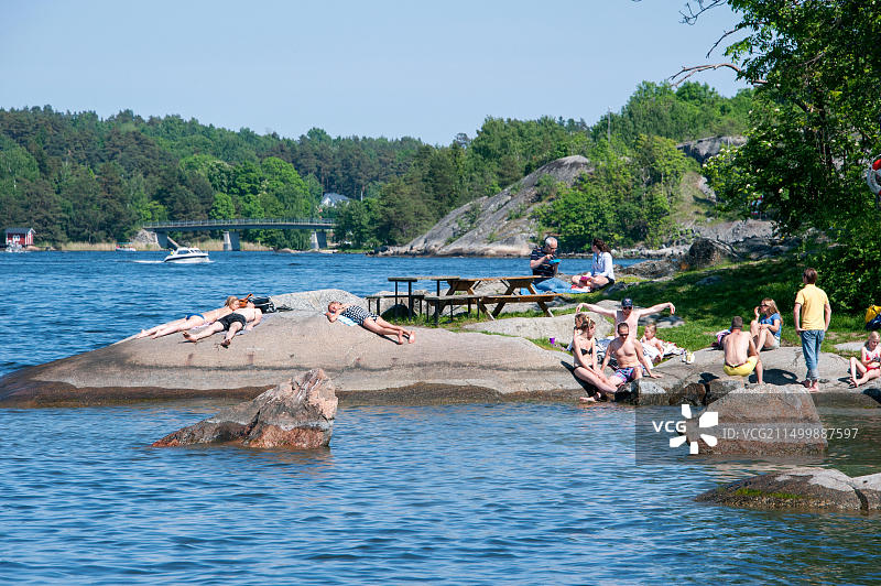 在斯德哥尔摩附近瓦克斯霍尔姆岛礁石海岸上享受日光浴的人们图片素材