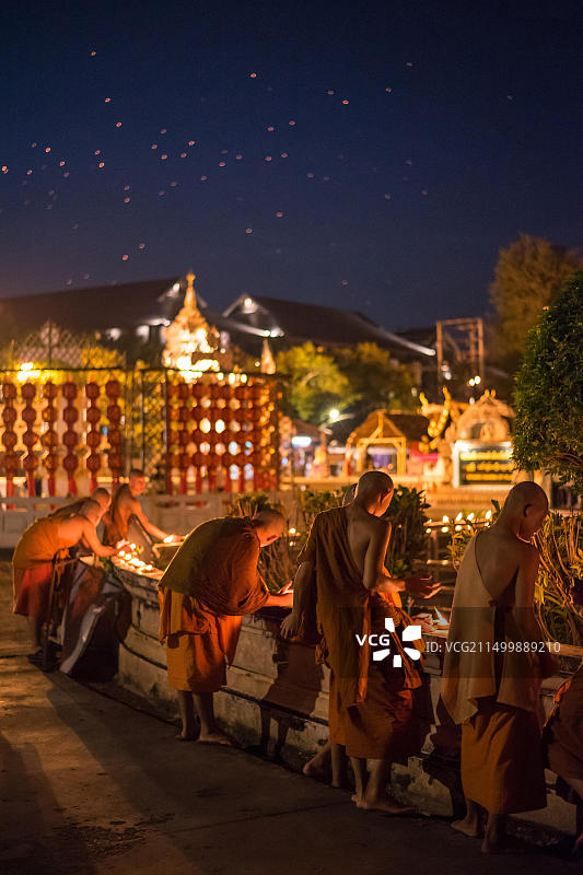 泰国清迈水灯节，僧侣在寺庙附近点燃陶土蜡烛碗，夜空中飘满孔明灯图片素材