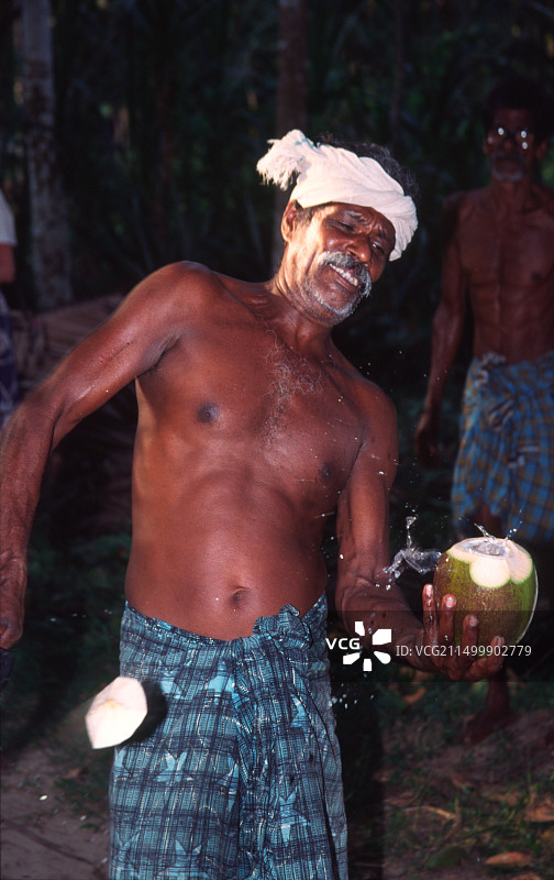 印度喀拉拉邦男子在内河切割椰子图片素材
