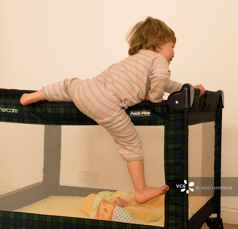 两岁男孩爬出婴儿床图片素材