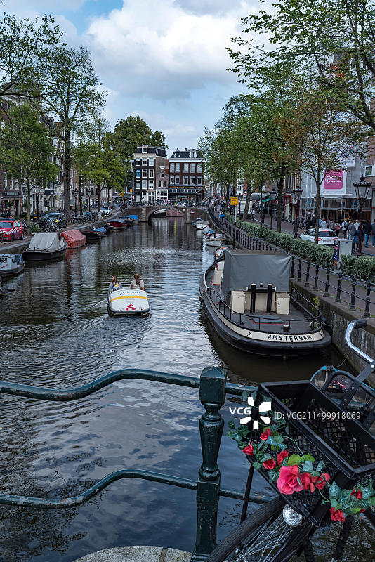 阿姆斯特丹运河上的系泊船只，前景为自行车和鲜花图片素材