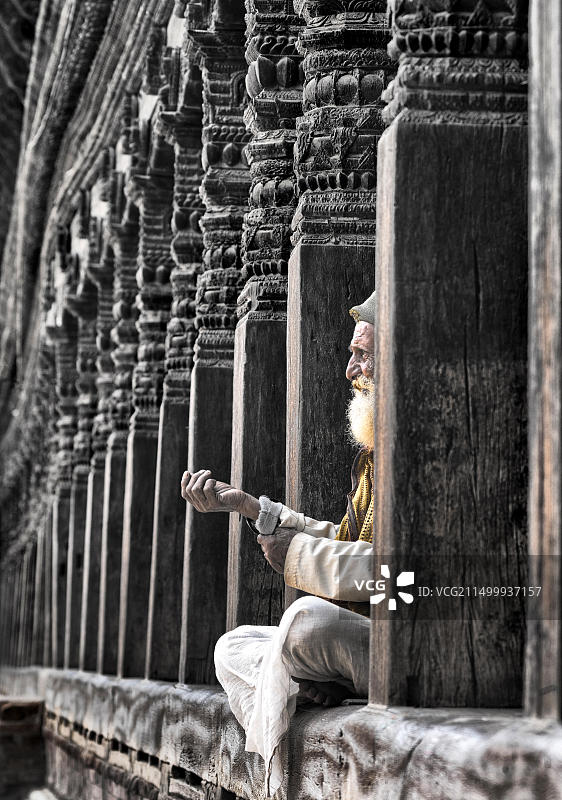 尼泊尔加德满都，坐在木制印度寺庙门阶上的年长男人肖像图片素材