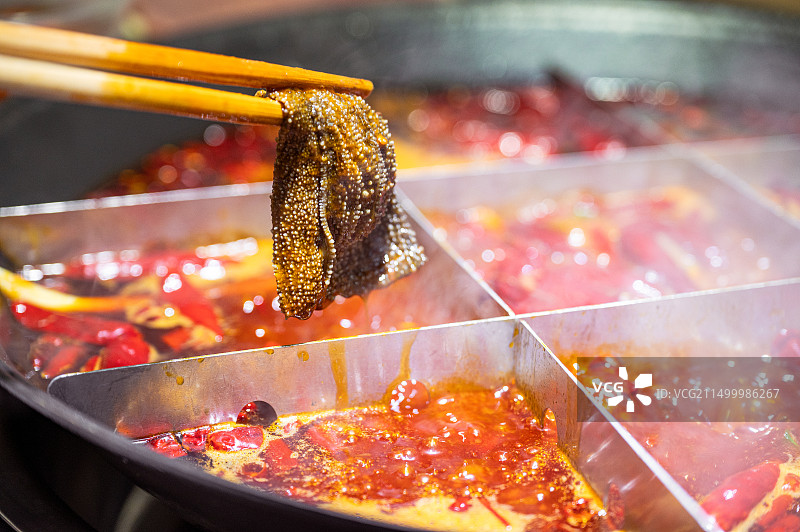 沸腾的九宫格火锅里面夹起的一片毛肚图片素材