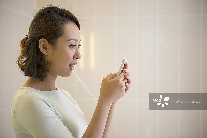 Young woman texting in bathroom图片素材