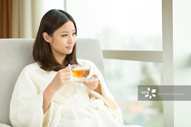年轻女孩在窗前喝茶图片素材