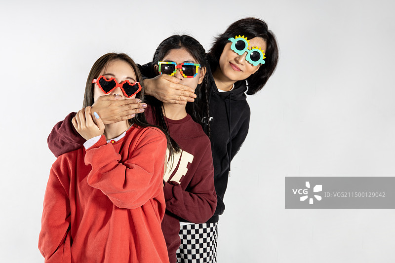 三个捂着嘴巴带着道具眼睛的女生图片素材