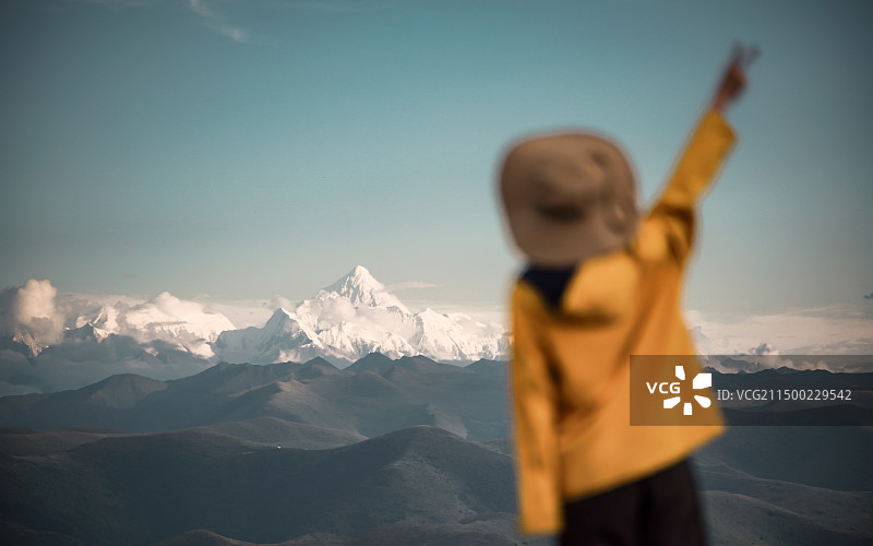 站在贡嘎雪山前的黄衣服女孩图片素材