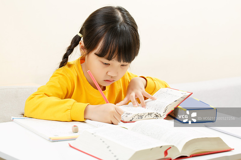 室内学习桌前写作业的中国小女孩图片素材