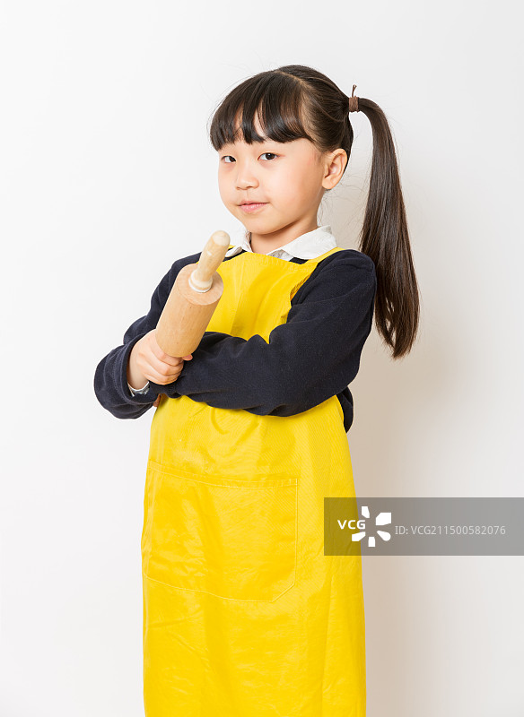 身穿黄色围裙手拿擀面杖的亚洲小女孩图片素材