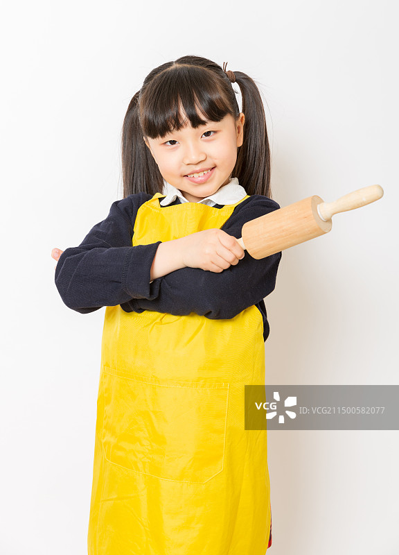 身穿黄色围裙手拿擀面杖的亚洲小女孩图片素材