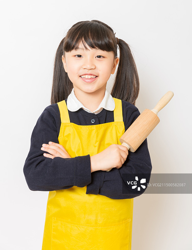 身穿黄色围裙手拿擀面杖的亚洲小女孩图片素材