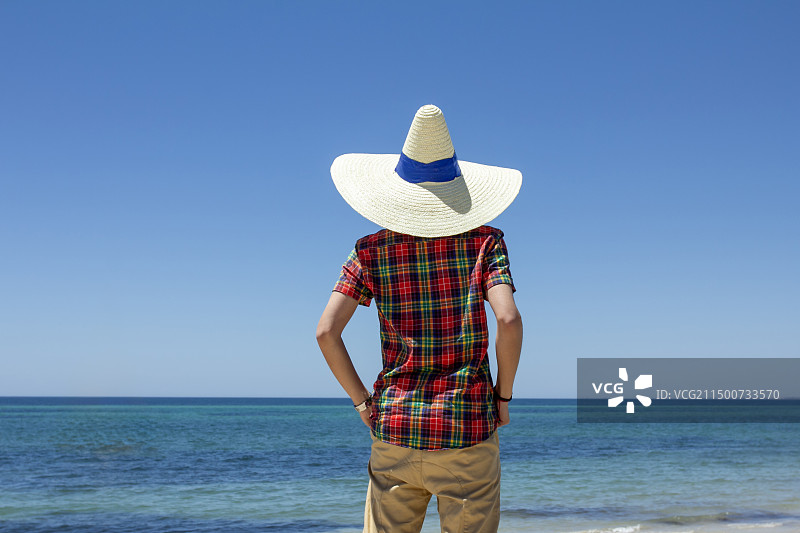 带草帽的男孩面向大海图片素材