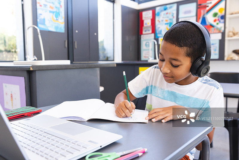 混血男孩在现代教室里用笔记本电脑学习图片素材