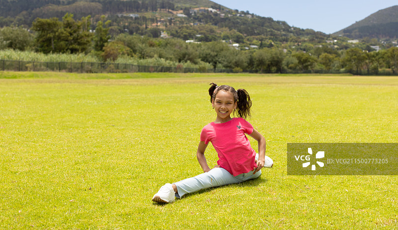 扎着辫子的混血女孩坐在公园草地上图片素材