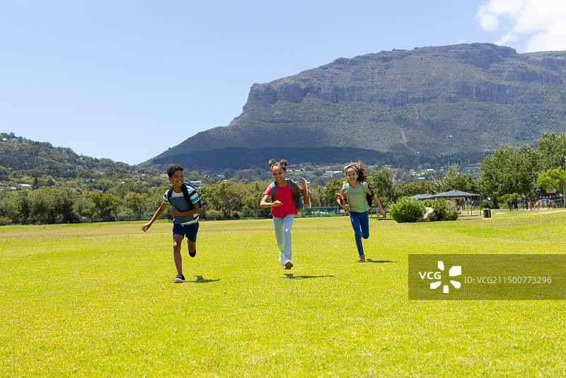 三个混血儿童在草地上奔跑，后面是山图片素材