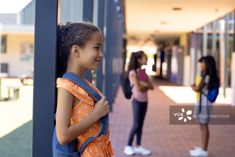 混血女孩穿着波点连衣裙站在学校的柱子旁微笑，有留白图片素材